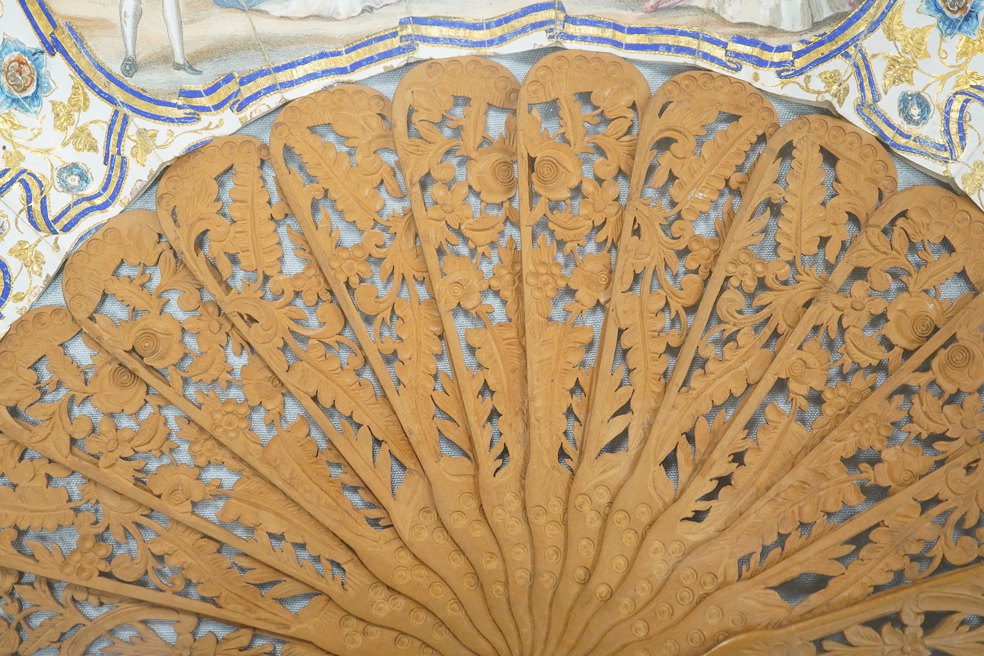 A gilt framed 19th century Spanish hand painted and decorated paper and sandalwood fan, from the Norte collection, the leaf painted with a central figurative cartouche and two others, surrounded with floral decoration an